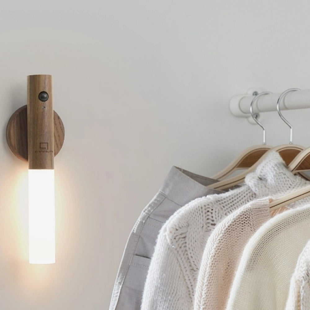 Wooden wall lamp next to a rack of clothes in a room.